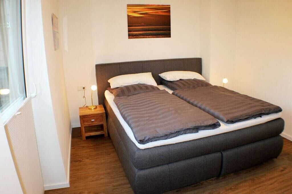 A single bed with a headboard, a bedside table with a lamp, and a wall-mounted picture.