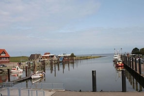 A calm waterway with boats docked, a pier, and buildings in the background. - Holiday apartment with 2 bedrooms (Fedderwardersiel-Butjadingen)