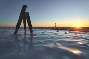 A sunset over a frozen landscape with a wooden structure in the foreground. - Holiday apartment with 2 bedrooms (Fedderwardersiel-Butjadingen)