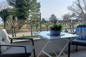 Een balkon met een tafel en stoelen, uitkijkend op een weiland met koeien.