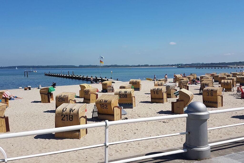 Une plage avec des chaises de plage numérotées et une jetée en arrière-plan.