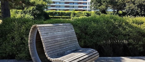 Un banc doté d’un dossier incurvé, placé sur une terrasse en bois.