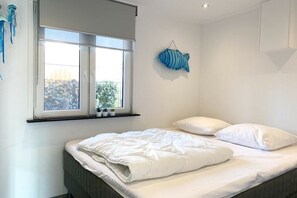 Ein Schlafzimmer mit Bett, Kissen, einem Fenster und einer Wanddekoration.