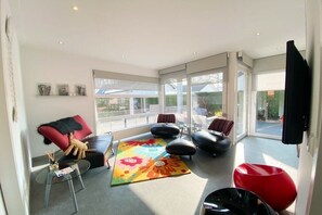 Ein modernes Wohnzimmer mit einer Couch, Hocker, einem Couchtisch und einem farbenfrohen Teppich.