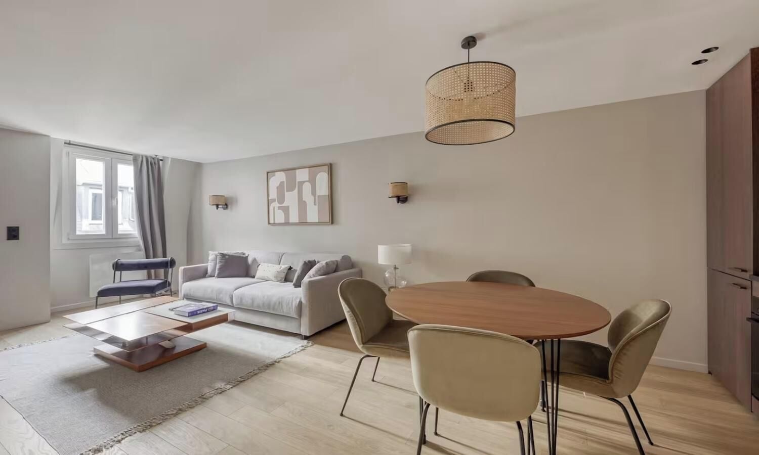 Uma sala de estar moderna com sofá, mesa de jantar com cadeiras, mesa de centro, luminária de chão e luminária pendente.