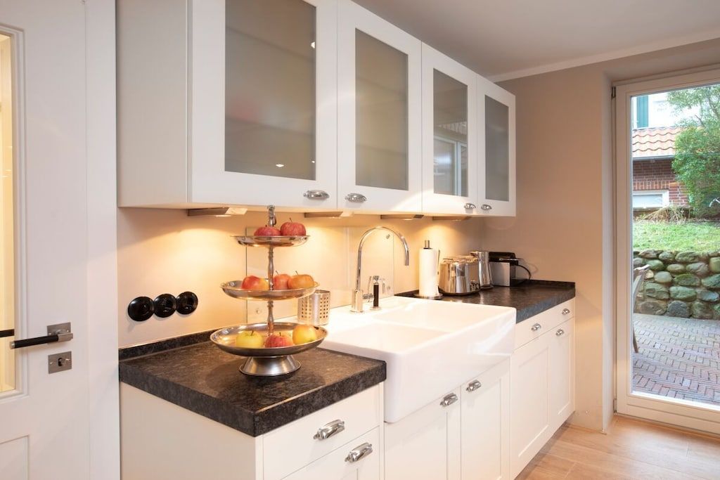 A kitchen with white cabinets, a black countertop, and a sink.