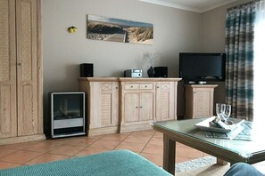 Ein Wohnzimmer mit Fernseher, Lautsprechern, Kamin und einem Bild an der Wand.