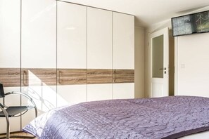 A bedroom with a bed, a wardrobe, and a chair. - Holiday apartment in Sylt with 1 bedroom (Wenningstedt)