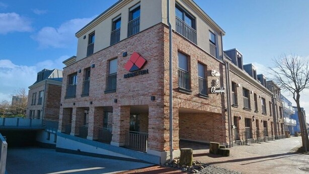 Un edifici de diversos pisos amb façana de maó, un logotip destacat i un balcó.