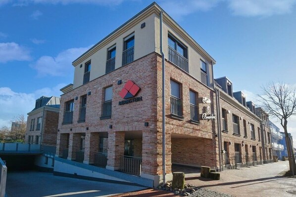 Ein mehrstöckiges Gebäude mit Ziegelverkleidung, einem auffälligen Logo und einem Balkon.