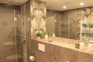 Ein modernes Badezimmer mit Duschkabine aus Glas, einem großen Spiegel und einem Handtuchhalter.