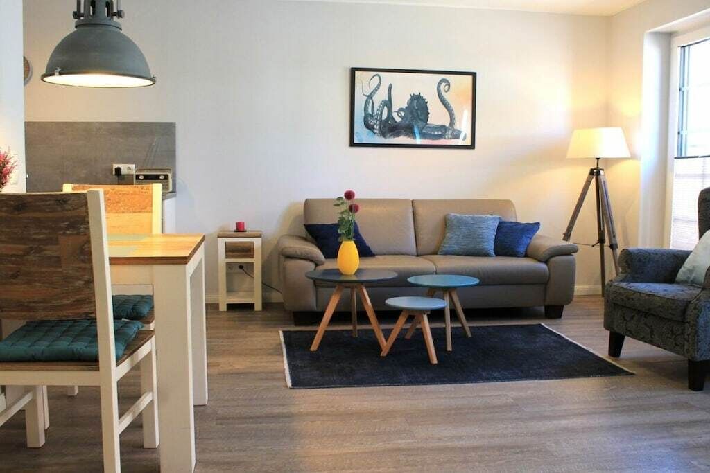 A modern living room with a sofa, two side tables, a lamp, and a painting on the wall.