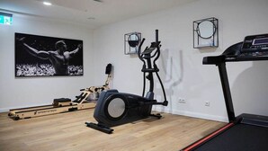 Una sala de fitness amb una màquina d'esquelles, una cinta el·líptica i un cinturó de córrer.