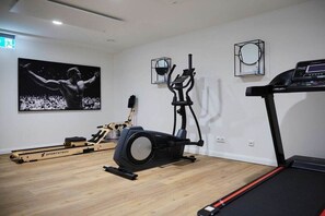 Ein Fitnessraum mit Rudergerät, Crosstrainer und Laufband.
