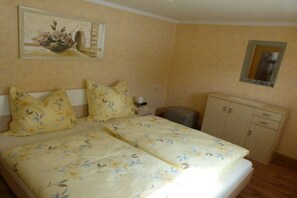 A bedroom with a bed, a nightstand, a cabinet, and a painting on the wall. - Mehnert's holiday apartment (Reinhardtsdorf)