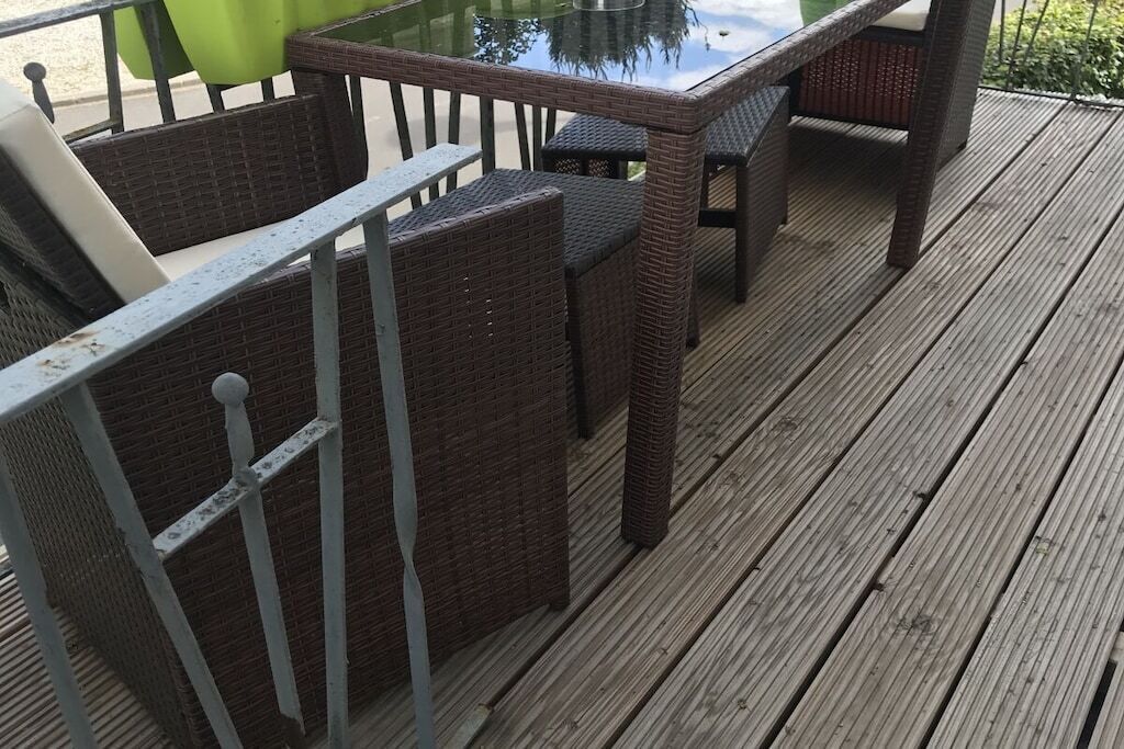 A deck with wicker furniture and a glass-top table.