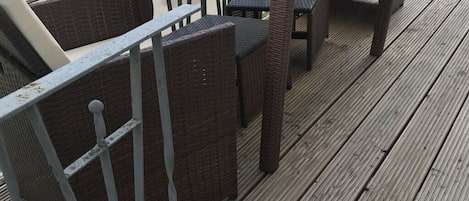 A deck with wicker furniture and a glass-top table.
