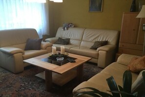A living room with a sofa, armchair, and a coffee table with candles. - Holiday home in Morbach with swimming pool (Morbach)