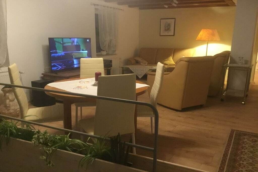 A living room with a television, a sofa, a table, and a lamp.