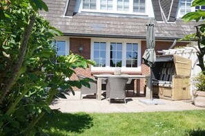 A patio with a table and chairs, a covered grill, and a white fence. - Holiday apartment with 2 bedrooms (Munkmarsch)