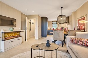 A modern kitchen with a built-in oven, a dining area with a round table and chairs, and a living room with a sofa and a patterned throw pillow. - Holiday apartment with 2 bedrooms (Munkmarsch)