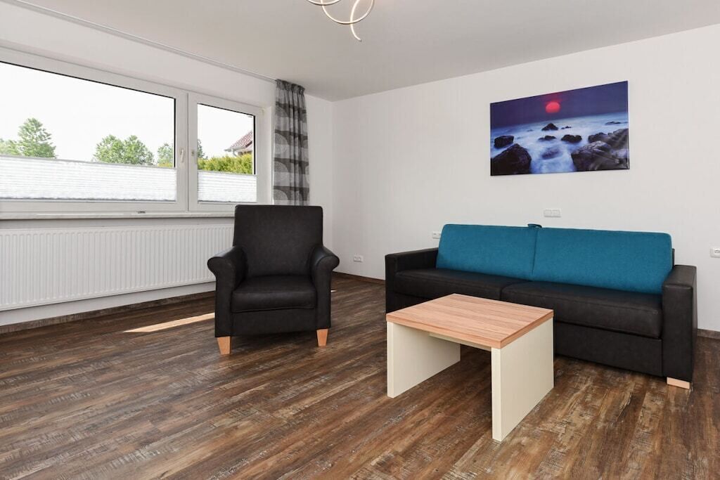 Una sala de estar moderna con un sillón de cuero negro, un sofá azul y una mesa de centro de madera.