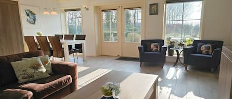 A spacious living area with a wooden coffee table, two sofas, and a dining table with chairs.