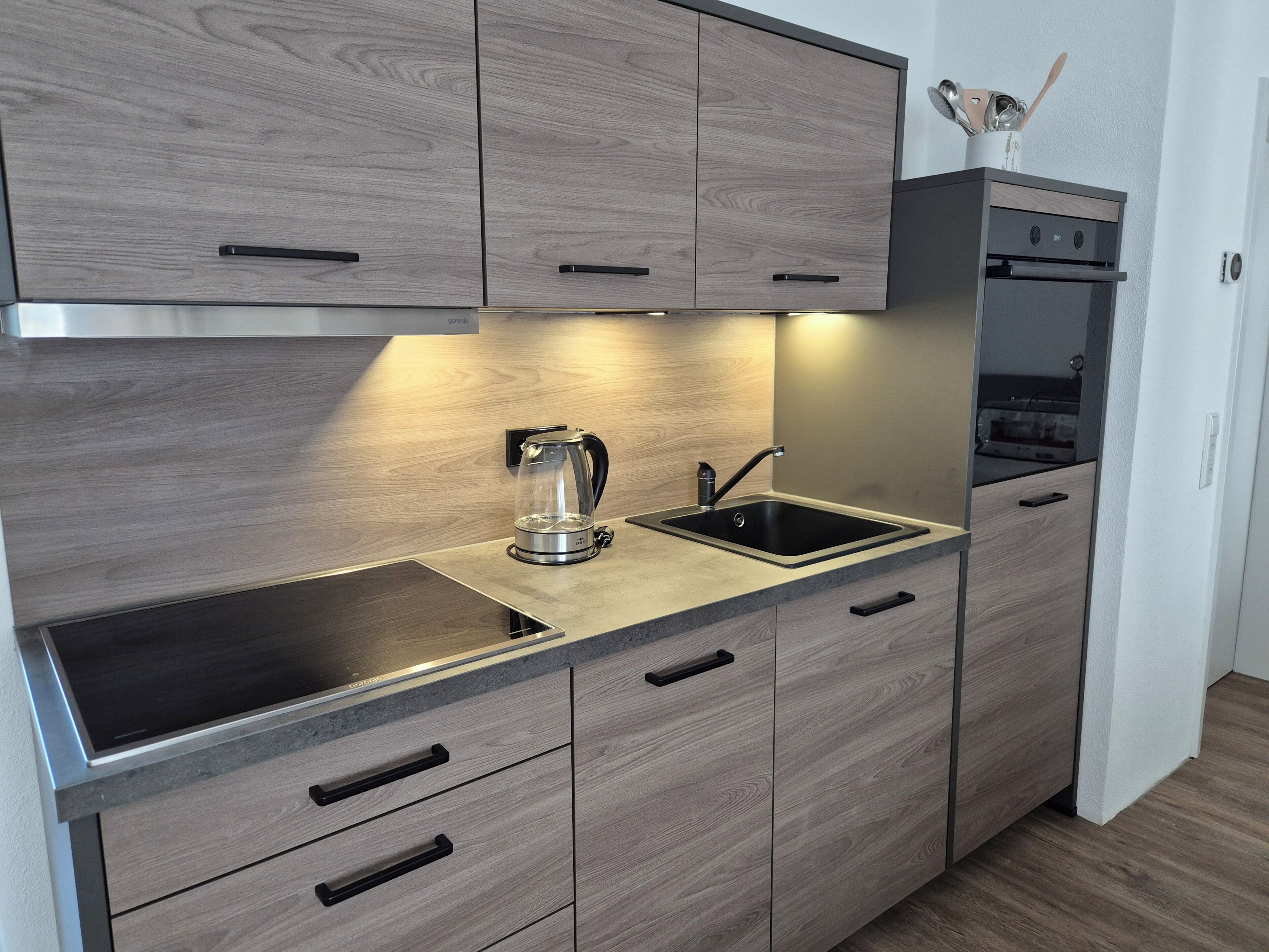 Eine moderne Küche mit Backofen, Wasserkocher und Spüle.