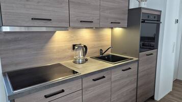 Eine moderne Küche mit Backofen, Wasserkocher und Spüle.