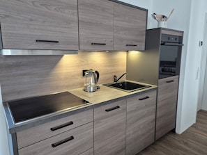 Una cocina moderna con horno empotrado, hervidor y lavabo.