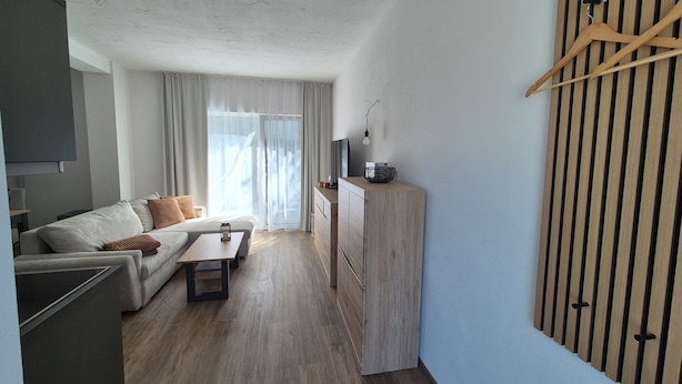 A modern living room with a sofa, coffee table, and a TV on a wooden cabinet.