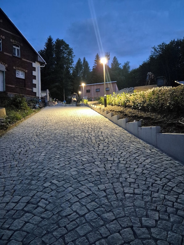 A cobblestone pathway leading to a building with a brick facade and a window.