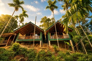 A two-story wooden house with a balcony, surrounded by tropical vegetation. - Nine Arch Jungle Inn (Ella)
