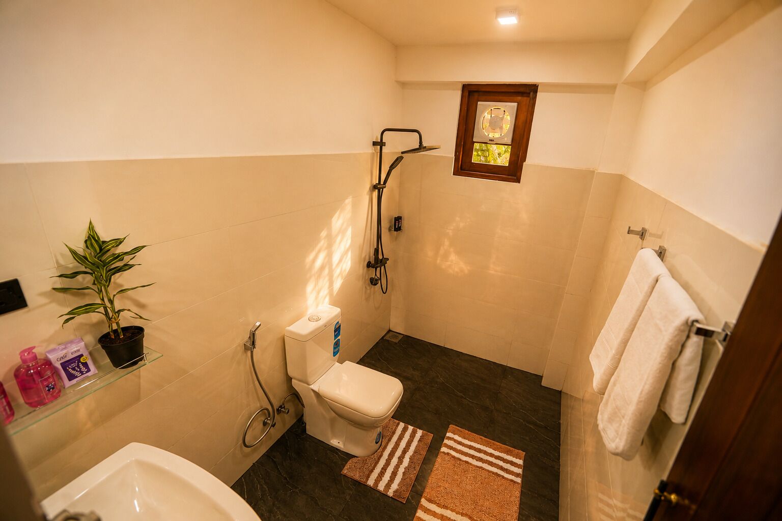 Une petite salle de bain comprenant des toilettes, une douche et une petite fenêtre.