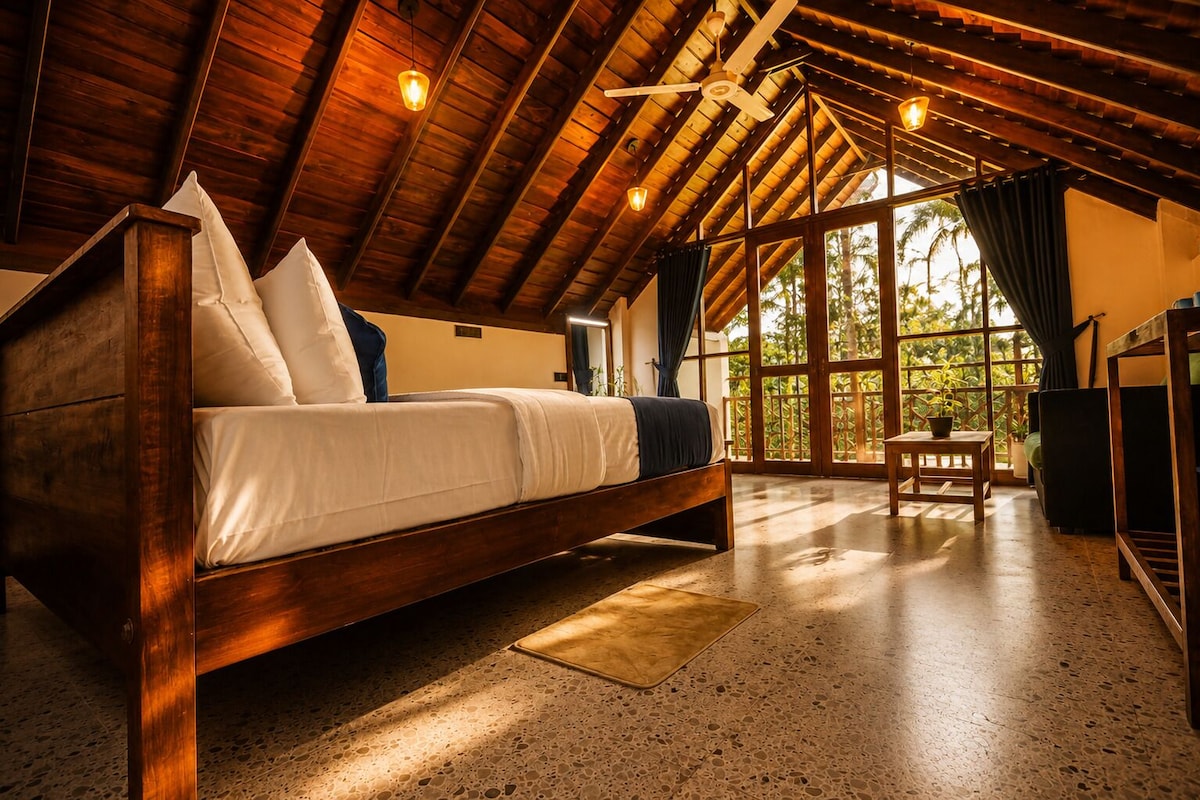 A spacious room with a large bed, a wooden ceiling, and a view through a glass door.