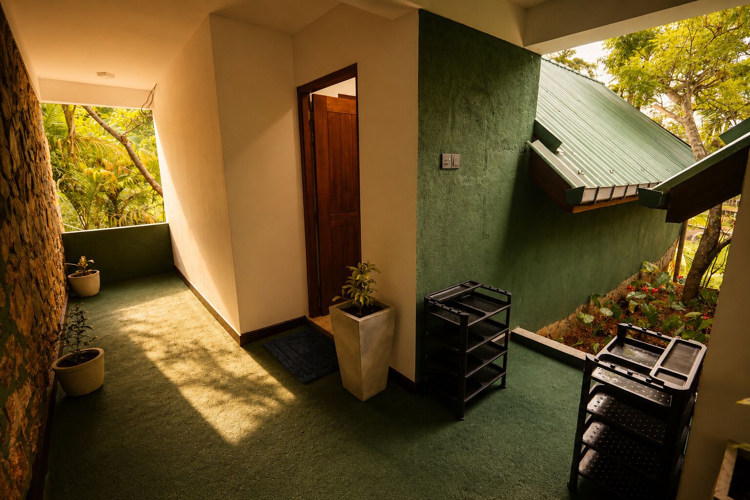 Un pasillo con pared verde, puerta de madera y una planta en maceta.