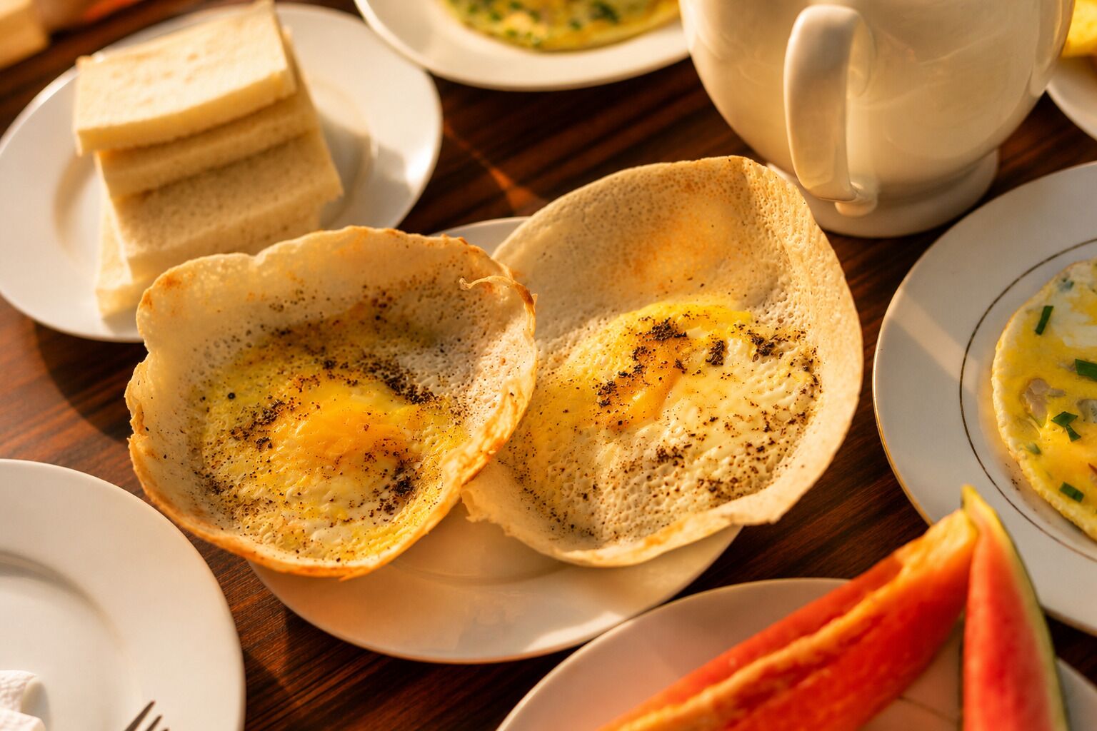 Un desayuno con crepas, tostadas y una taza de café sobre una mesa de madera.