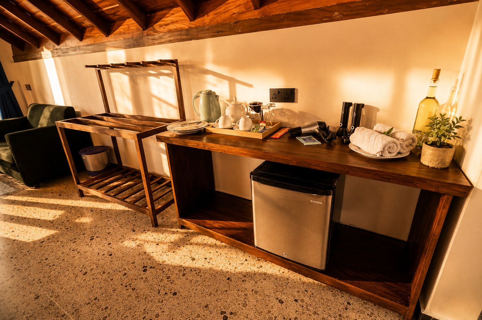 Una cocina funcional con una mesa de madera, un lavamanos y un refrigerador pequeño.