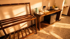 A kitchen with a wooden bench, a countertop with kitchenware, and a dishwasher.