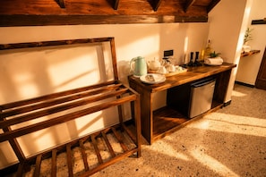 A kitchen with a wooden bench, a countertop with kitchenware, and a dishwasher. - Nine Arch Jungle Inn (Ella)