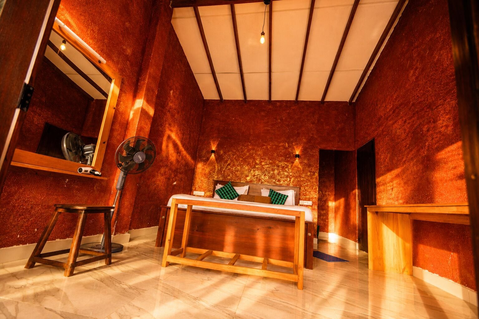 Quarto com uma cama, um ventilador e um espelho.
