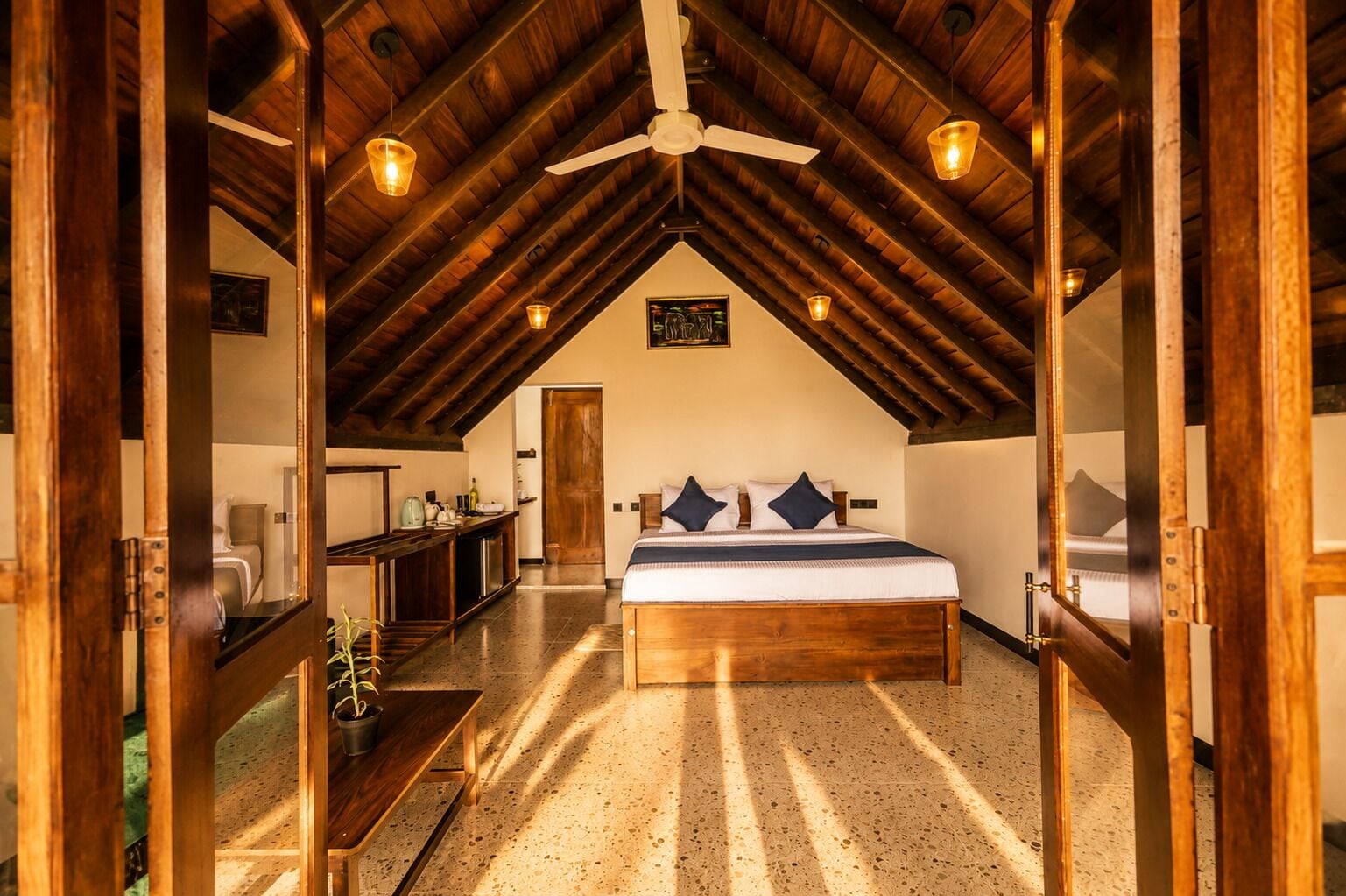 A bedroom with a wooden ceiling, a bed with pillows, a bedside table, and a mirror.