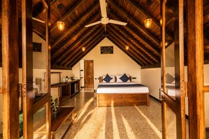 A bedroom with a wooden ceiling, a bed with pillows, a bedside table, and a mirror.