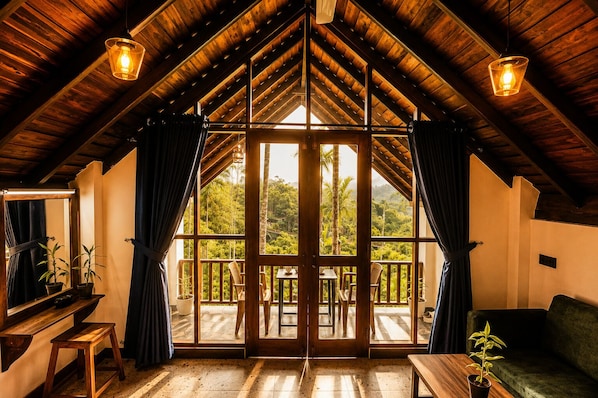 Una habitación con techo de madera inclinado, ventanas amplias y vistas a un paisaje exuberante.