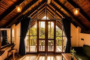 A room with a sloped wooden ceiling, large windows, and a view of a lush landscape.