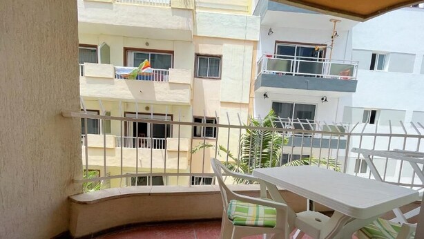 A balcony with a table and chairs, a view of adjacent buildings, and a railing. - Edificio Playa (Los Cristianos)