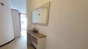 A hallway with a white wall, a wooden bench, and a mirror. - Edificio Playa (Los Cristianos)
