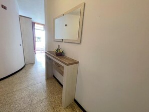 A hallway with a white wall, a wooden bench, and a mirror. - Edificio Playa (Los Cristianos)