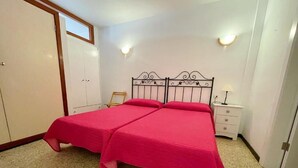 A room with a double bed, a wardrobe, a nightstand, and two wall-mounted lights. - Edificio Playa (Los Cristianos)