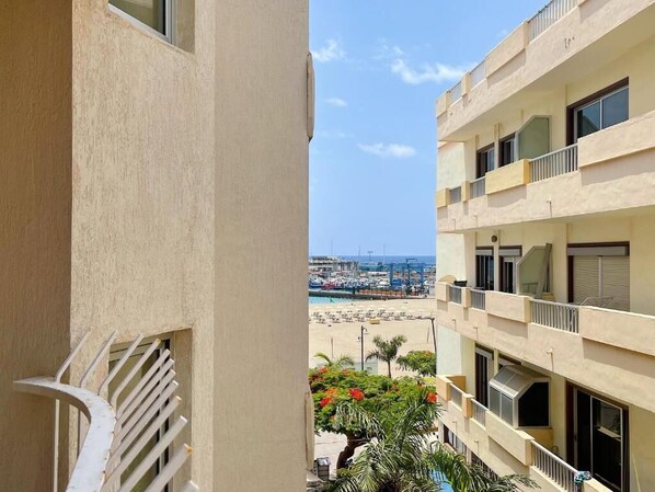 A multi-story building with balconies overlooking a marina and beach. - Edificio Playa (Los Cristianos)